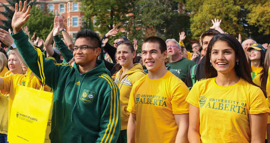 Four students sitting and smiling at each other in Main Quad on North Campus.