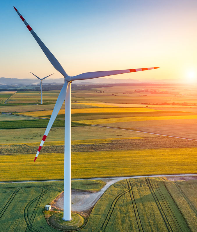 Wind turbines in a field against a sunrise