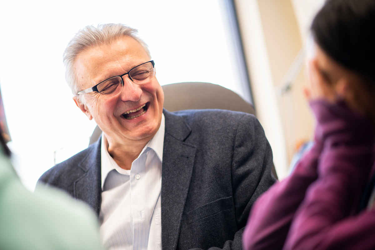 Professor of mathematics, Dragos Hrimiuc, laughing with students in his office