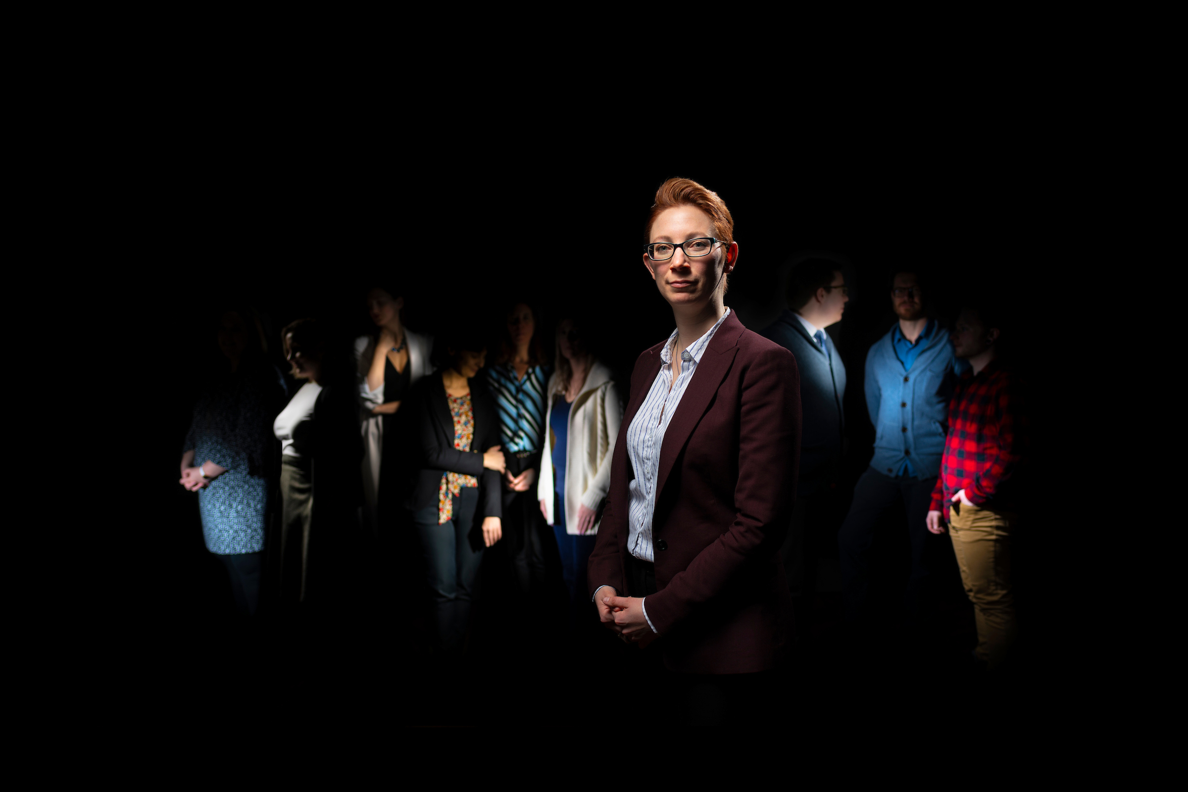 Lisa Willis standing in front of a faded group of 6 women and 3 men