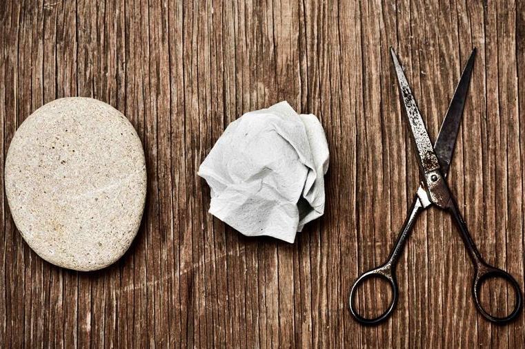 Rock, paper, and scissor, pictured on a table.