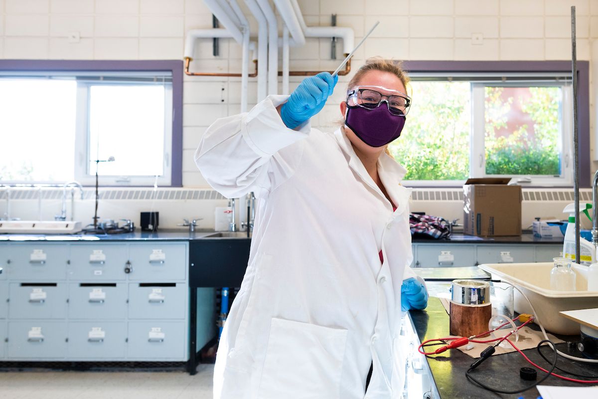 A student works at a lab bench in an undergraduate chemistry lab while wearing a face mask.